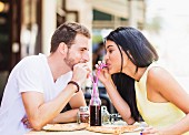 A couple sharing a cola at a pavement cafe