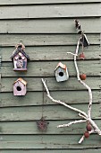 Weathered birdhouse on wooden wall with white branch decorated nostalgically