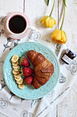 A sweet breakfast with a croissant, fruit, jam and coffee