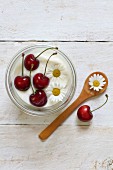 Yoghurt garnished with cherries and daisies (seen from above)