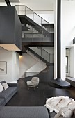 Staircase and suspended fireplace in double-height black-and-white interior