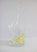 Ein spritzender Gin Tonic im Glas vor weißem Hintergrund