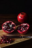 A halved pomegranate on a wooden chopping board