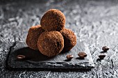 Truffle pralines with coffee beans on a black stone