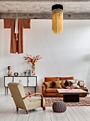 Retro furniture, concrete ceiling and ethnic clothing hung on wall above sideboard in living area