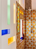 Vintage-style shower fitting on ornate wall tiles and stained-glass niches