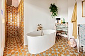 Free-standing modern bathtub in eclectic bathroom with shower area and ornate floor and wall tiles