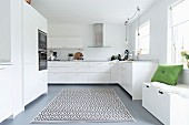 Storage bench below window and rug with graphical pattern in elegant white fitted kitchen