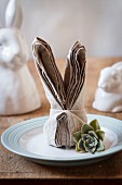 A dinner place set with a folded bunny napkin and a succulent plant