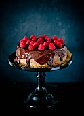 A whole chocolate cheesecake with chocolate glaze and raspberries