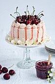 A whole Victoria sandwich cake with fresh cherries