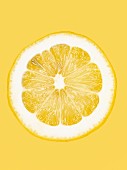 Aufgeschnittene gelbe Zitrone vor gelbem Hintergrund, Close-Up