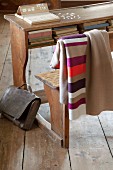 Striped and plain blankets made from warm, boiled wool hung over backrest of vintage school bench