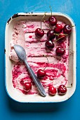 Cherry ice cream in an enamel dish with an ice cream scoop