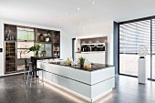 A white kitchen island with base lighting in an open-plan designer kitchen
