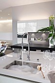 Kitchen island with an integrated sink, washing-up water and glasses