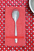 Spoon on red linen napkin and table mat made from red-painted wooden discs