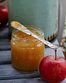 Apple, ginger and lemon jam in a glass jar with a knife