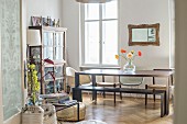 Display case, wooden table and various chairs in dining area of period apartment