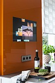 An orange glass panel with an integrated screen in a kitchen