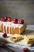 Cherry cake with icing, fresh cherries and flaked almonds, sliced