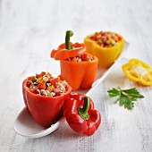 Rote, gelbe und orangefarbene Paprika, gefüllt mit Salat aus Reis, Paprika und Tomaten