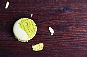 A crumbled pistachio macaroon on a wooden surface