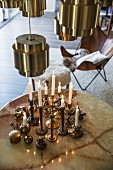 Brass candlesticks on round table below brass lampshades