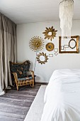 Cane chair with cushions below sunburst mirrors on bedroom wall