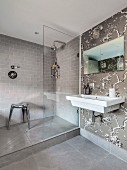 Elegantes Bad in Grautönen mit Duschbereich und floraler Tapete an Wand