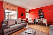 Lounge furniture and desk against red walls in renovated period apartment