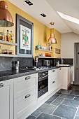 White kitchen counter with granite worksurface below shelves mounted on yellow wall