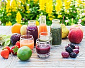 Various smoothies in glasses and bottles with fruit and salad