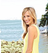 Junge blonde Frau in gelbem Sommerkleid am Meer