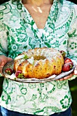 Frau hält Rhabarber-Erdbeer-Kuchen mit Puderzucker