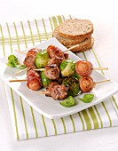 Sausages wrapped in bacon and Brussels sprouts on skewers
