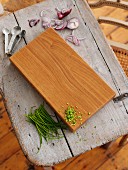 A wooden board with chives, red onions and measuring spoons