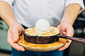 A waiter holding a small pan of dessert