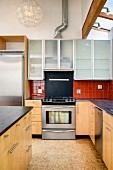 Cooker, dark worksurfaces and cabinets in modern kitchen