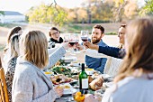 Friends raising glasses of wine outside at an autumnal decorated table