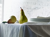 Two Abate Fetel pears on a table with a white tablecloth