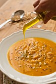 Pumpkin soup being drizzled with olive oil