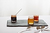 Various jars of honey on a slate platter