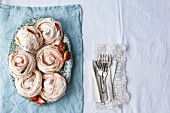Meringues with strawberry swirls and fresh strawberries on a serving platter