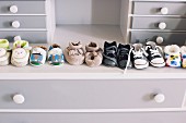 Aufgereihte Babyschuhe auf einer grauen Kommode