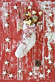 A Christmas stocking filled with nuts and biscuits on a red and white wooden surface