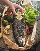 A whole roasted salmon with vegetables in baking paper