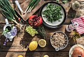Zutatenstilleben mit Salat, Grütze, Granatapfel, Frühlingszwiebeln, Kräutern und Zitronen