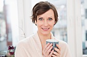 Lächelnde Frau hält Kaffeetasse in den Händen