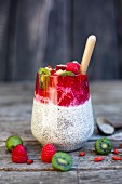 Chia-Pudding im Glas mit Kokos, Himbeersauce, Mini-Kiwis und Gojibeeren